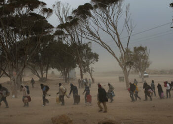 Men, who used to work in Libya and fled the unrest in the country, carry their belongings as they arrive during a sand storm in a refugee camp at the Tunisia-Libyan border, in Ras Ajdir, Tunisia, Tuesday, March 15, 2011. More than 250,000 migrant workers have left Libya for neighboring countries, primarily Tunisia and Egypt, in the past three weeks. (AP Photo/Emilio Morenatti)