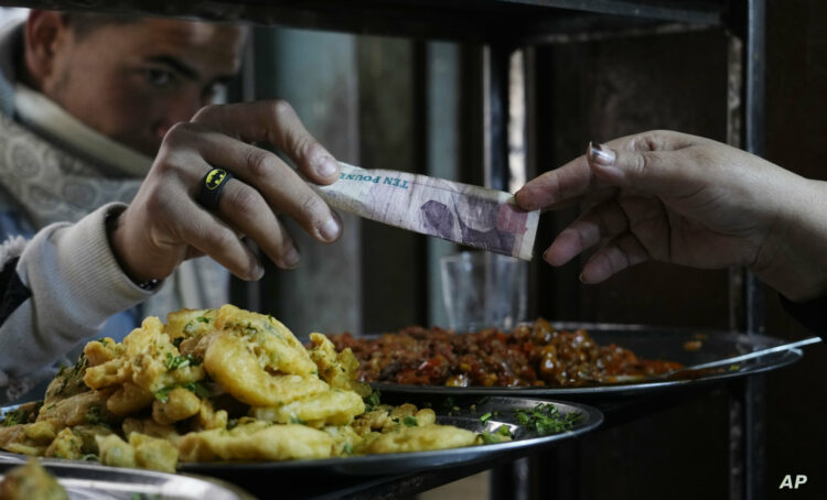 A man buys food at a popular restaurant in Cairo, Egypt, Tuesday, March 22, 2022. Egypt's Central Bank raised its key interest rate Monday for the first time since 2017, citing inflationary pressures triggered by the coronavirus pandemic and Russia's war in Ukraine. The move saw the Egyptian pound slip, trading at over 18 to the dollar — up from an average of 15.6 pounds for $1. That was likely to take a heavy toll on poor and middle-class Egyptians. (AP Photo/Amr Nabil)