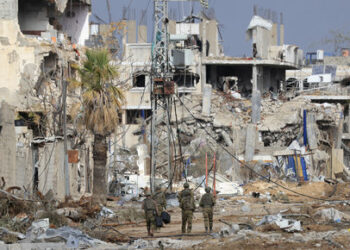 Israeli troops walk past destroyed buildings along the Salaheddine road which links the northern Gaza Strip with the south in the Zeitoun district on the outskirts of Gaza City on November 28, 2023. A truce between Israel and Hamas entered a fifth day on November 28 after the deal was extended to allow further releases of Israeli hostages and Palestinian prisoners. (Photo by MAHMUD HAMS / AFP)