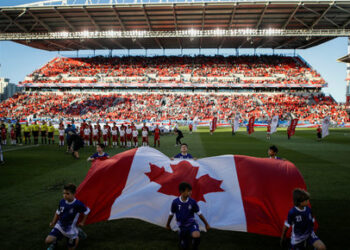 Kids hold a Canadian flag during the national anthem before the Toronto FC play D.C. United in their MLS soccer match, at BMO Field, a venue for the 2026 FIFA World Cup, in Toronto, Ontario, Canada, June 13, 2018.    REUTERS/Mark Blinch