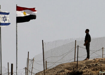 An Egyptian soldier stands near the Egyptian national flag and the Israeli flag at the Taba crossing between Egypt and Israel, about 430 km (256 miles) northeast of Cairo, October 26, 2011. Israel and Egypt said on Monday they have struck a deal to swap 25 Egyptians in Israeli custody for a U.S.-Israeli dual national accused by Cairo of espionage, in a step seen as easing strains between the strategic neighbors. REUTERS/Mohamed Abd El-Ghany  (EGYPT - Tags: CIVIL UNREST POLITICS)