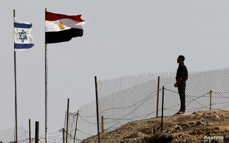 An Egyptian soldier stands near the Egyptian national flag and the Israeli flag at the Taba crossing between Egypt and Israel, about 430 km (256 miles) northeast of Cairo, October 26, 2011. Israel and Egypt said on Monday they have struck a deal to swap 25 Egyptians in Israeli custody for a U.S.-Israeli dual national accused by Cairo of espionage, in a step seen as easing strains between the strategic neighbors. REUTERS/Mohamed Abd El-Ghany  (EGYPT - Tags: CIVIL UNREST POLITICS)