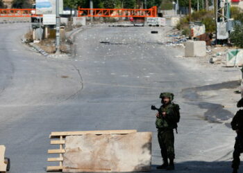 Israeli soldiers stand guard on a blocked road, as the entrance to Hebron is closed, in the Israeli-occupied West Bank, October 8, 2023. REUTERS/Mussa Qawasma