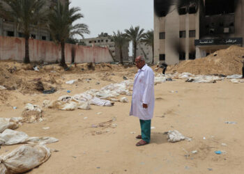 A doctor stands near bodies lined up for identification after they were unearthed from a mass grave found in the Nasser Medical Complex in the southern Gaza Strip on April 25, 2024, amid the ongoing conflict between Israel and the Palestinian militant group Hamas. The head of Gaza's Civil Defence agency in Khan Yunis, raised to 392 the number of bodies he said had been recovered from three mass graves at the city's Nasser Medical Complex. (Photo by AFP)