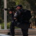 An Israeli police officer points his gun, at the scene of a shooting attack at Tekoa Junction in the Israeli-occupied West Bank, July 16, 2023. REUTERS/Dedi Hayun