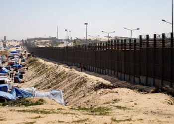 People walk near the border with Egypt, as displaced Palestinians, who fled their houses due to Israeli strikes, shelter at a tent camp, amid the ongoing conflict between Israel and the Palestinian Islamist group Hamas, in Rafah in the southern Gaza Strip, February 29, 2024. REUTERS/Ibraheem Abu Mustafa
