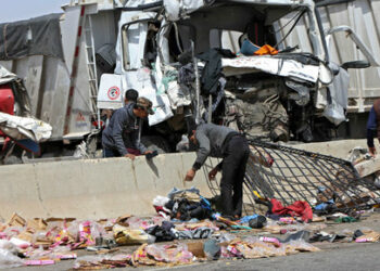 Workers inspect the wreckage of a car at the site of a road accident near the town of Al-Saff in Cairo's northern Giza province, some 40 kilometres North of the capital, on March 26, 2020, which left several people killed and wounded. (Photo by Khaled KAMEL / AFP)