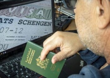 A Moroccan man holds his passport in front of his computer displaying a Schengen visa in the capital Rabat, on September 28, 2021. Paris will sharply reduce the number of visas granted to people from Algeria, Morocco and Tunisia, accusing the former French colonies of not doing enough to allow illegal immigrants to return, a government spokesman said today. (Photo by FADEL SENNA / AFP)