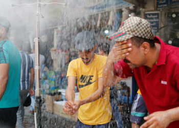 People cool off under an outdoor shower as the temperature soars in Baghdad, Iraq July 28, 2020. REUTERS/Thaier Al-Sudani