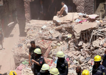 A man sits on the rubble waiting as Egyptian emergency and rescue personnel search for survivors in the rubble of a five-story apartment building that collapsed, leaving several people dead, according to authorities, in Hadaeq al-Qubbah neighborhood, in Cairo, Egypt, July 17, 2023. REUTERS/Mohamed Abd El Ghany