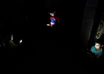 Kids hold their mobile phones during the power off time that the government applied to overcome the overload amid a heatwave, as Egyptians experience frequent power cuts, after the government said lack of natural gas supplies feeding the country's electricity grid has fueled the crisis, in Cairo, Egypt, June 25, 2024. REUTERS/Mohamed Abd El Ghany