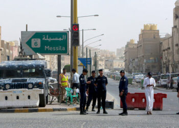 Kuwaiti police officers man a checkpoint at the entrance the town of Jeleeb Al-Shuyoukh, south the capital Kuwait City on April 7, 2020, after the district was put on lockdown. (Photo by YASSER AL-ZAYYAT / AFP)