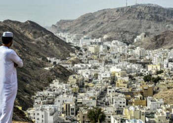 (FILES) A man stands atop a hill in al-Wadi al-Kabir west of Oman's capital Muscat on February 14, 2018 while waiting for the peloton during the second stage of the 2018 cycling Tour of Oman. Four people were killed and multiple others wounded in a shooting at the Imam Ali Mosque in the Al-Wadi Al-Kabir, police said on July 16, 2024. Such an attack is rare in the Sultanate, which has regularly played the role of mediator in regional conflicts. Shiites this week mark Ashura, an annual day of mourning that commemorates the 7th-century battlefield martyrdom of Hussein. (Photo by Philippe LOPEZ / AFP)