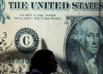 A woman walks past a currency exchange point, displaying an image of the U.S. dollar, in Cairo, Egypt, March 6, 2024. REUTERS/Mohamed Abd El Ghany