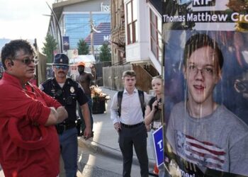 A man walks by a poster depicting Thomas Matthew Crooks, the man that attempted to assassinate former President Donald Trump during the third day of the 2024 Republican National Convention near the Fiserv Forum, Wednesday, July 17, 2024, in Milwaukee. (AP Photo/Alex Brandon)