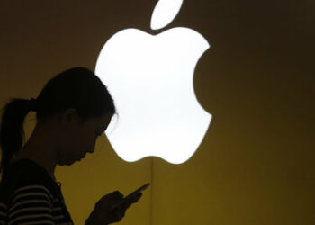 A woman looks at the screen of her mobile phone in front of an Apple logo outside its store in downtown Shanghai September 10, 2013. Apple Inc is expected to introduce a cheaper version of the iPhone on Tuesday, bringing one of the industry's costliest smartphones within reach of the masses in poorer emerging markets. The world's most valuable technology company, which many expect to unveil an iPhone 5C in several colors alongside the latest high-end iPhone 5S, is trying to beat back rivals like Samsung Electronics Co Ltd and Huawei Technologies Co Ltd in markets like India and China, where it is fast losing ground.       REUTERS/Aly Song  (CHINA - Tags: BUSINESS SCIENCE TECHNOLOGY TELECOMS)