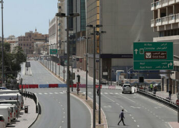 A pedestrian crosses a road near a police road block during a full lockdown, following the outbreak of the coronavirus disease (COVID-19), in the Al Ras neighbourhood in Dubai, United Arab Emirates, March 31, 2020. REUTERS/Christopher Pike