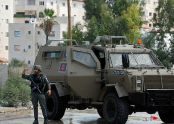 An Israeli soldier gestures next to a military vehicle during raid in Tulkarm, in the Israeli-occupied West Bank, August 22, 2024. REUTERS/Raneen Sawafta