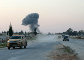 Anti-regime fighters drive along the Aleppo- Damascus M5 international highway in the newly captured northwestern area of Khan al-Assal, as smoke rises in the distance on November 29, 2024. Jihadists and their Turkish-backed allies took control of five districts of Syria's second city of Aleppo on November 29, "without any significant pushback" from the Syrian military, a war monitor said. (Photo by AFP)