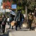 Anti-government fighters cross the path of residents carrying their belongings in Aleppo on November 30, 2024. Jihadists and their Turkish-backed allies breached Syria's second city of Aleppo on November 29, as they pressed a lightning offensive against forces of the Iranian- and Russian-backed government. (Photo by MUHAMMAD HAJ KADOUR / AFP)