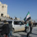 A man holds a Syrian Opposition flag at Aleppo's ancient citadel, after the Syrian army said that dozens of its soldiers had been killed in a major attack by rebels who swept into the city, in Aleppo, Syria November 30, 2024. REUTERS/Mahmoud Hassano