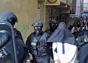 Members of Moroccos's Central Bureau of Judicial Investigation (BCIJ), which oversees counter-terrorism operations, escort a suspect outside a house in the city of Tangier, on October 6, 2021. (Photo by AFP)