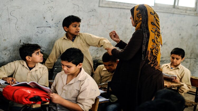 "نُدرّس منذ سنوات بلا حقوق".. معلمو الحصة يصرخون: التثبيت أو الكرامة! 1 GIZA, EGYPT - OCTOBER 30: An Egyptian student is punished by his teacher during the lesson at a primary school, where nearly 2 thousand students get education, after the Egyptian national anthem performance in Baragil neighborhood of Giza, Egypt on October 30, 2014. Head master of the school complains about the crowded classroom sizes, reaching up to 70, lack of the desks and other impossibilities. Formal education, at every level, is provided freely at state schools in Egypt. Downswing due to the ongoing 4-year unrest, Egypt tries to overcome many difficulties and uncertainties. (Photo by Mohamed Hossam/Anadolu Agency/Getty Images)