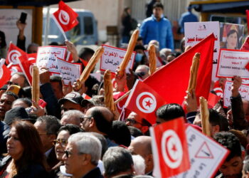 Demonstrators hold placards, Tunisian national flags and baguettes during a protest against Tunisian President Kais Saied's seizure of governing powers, in Tunis, Tunisia March 13, 2022. REUTERS/Zoubeir Souissi