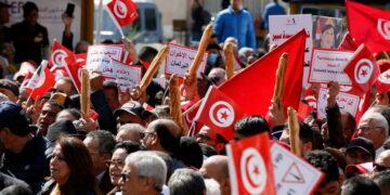 Demonstrators hold placards, Tunisian national flags and baguettes during a protest against Tunisian President Kais Saied's seizure of governing powers, in Tunis, Tunisia March 13, 2022. REUTERS/Zoubeir Souissi