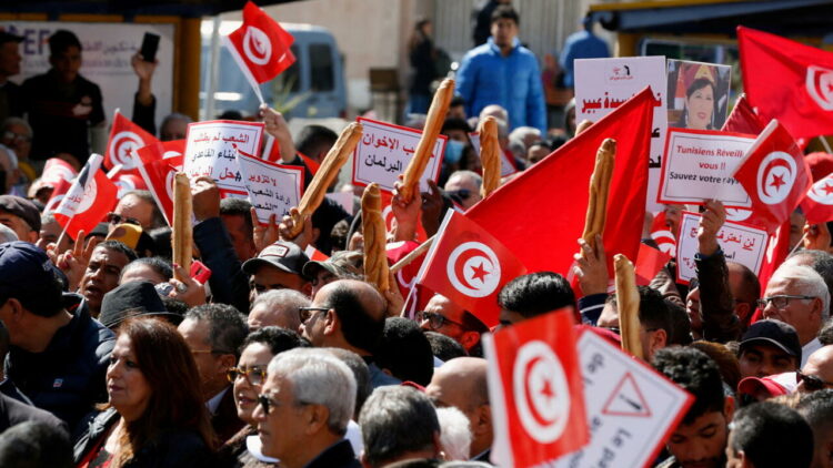 Demonstrators hold placards, Tunisian national flags and baguettes during a protest against Tunisian President Kais Saied's seizure of governing powers, in Tunis, Tunisia March 13, 2022. REUTERS/Zoubeir Souissi